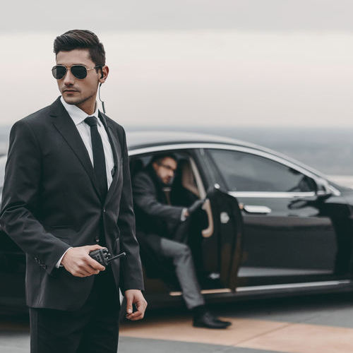 bodyguard with portable radio standing at businessman car